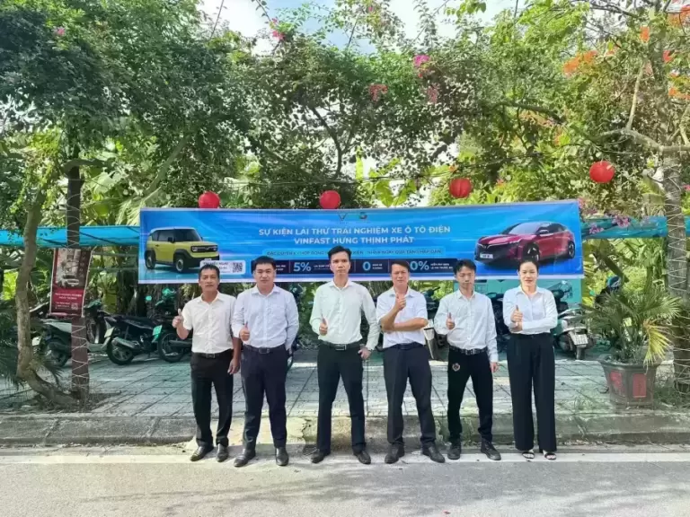 Nhân viên VinFast Hưng Thịnh Phát bên banner sự kiện lái thử VF 3 vàng, VF 8 đỏ tại Quỳnh Phụ