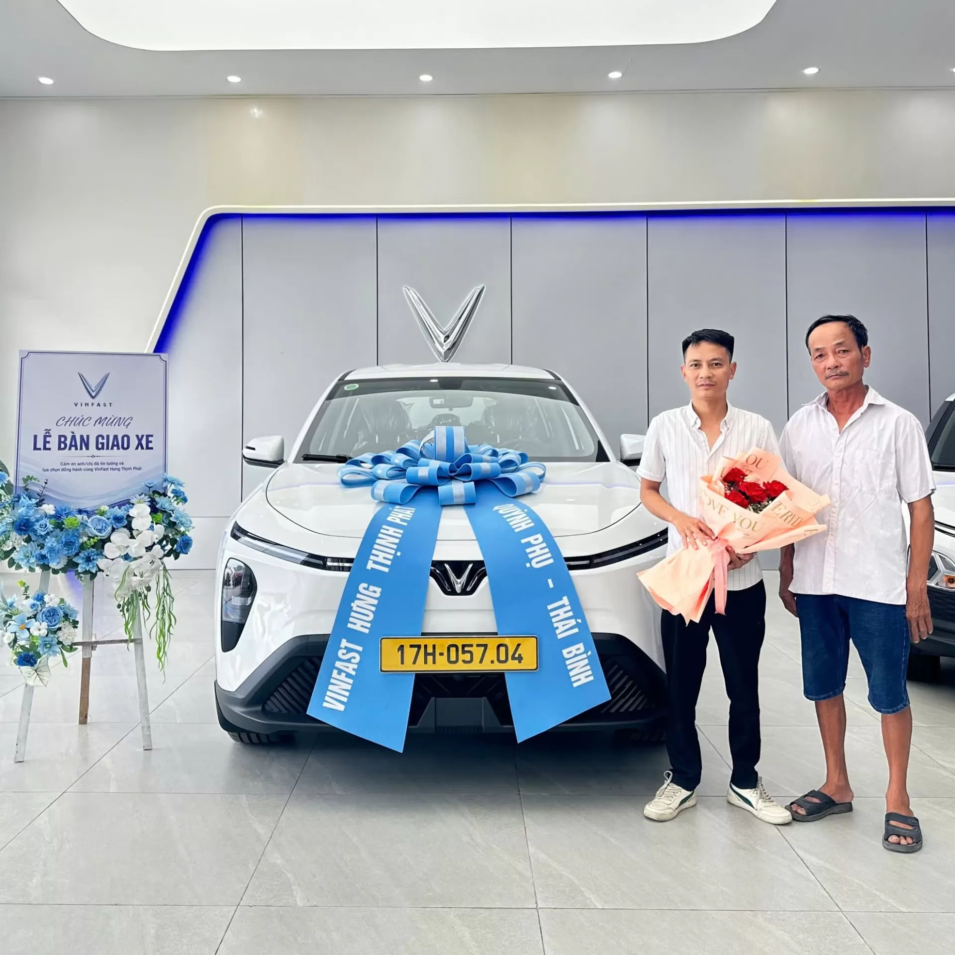 Hai khách hàng nhận bàn giao xe điện VinFast màu trắng thắt nơ xanh