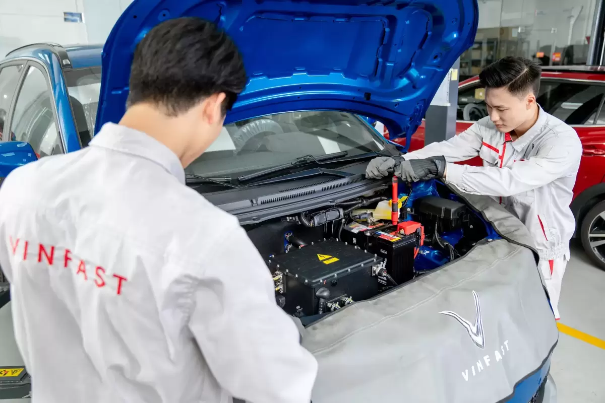 Hai kỹ thuật viên đang kiểm tra khoang động cơ xe điện VinFast màu xanh