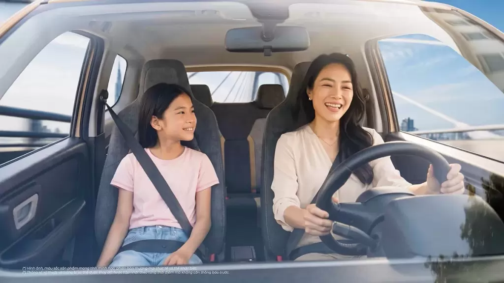 Người phụ nữ mỉm cười lái xe VinFast VF 2 cùng con gái ngồi bên cạnh