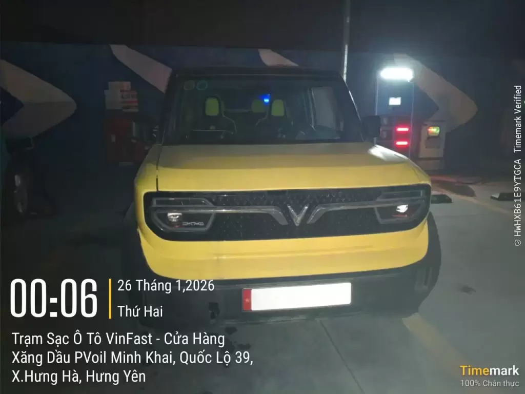 Xe ô tô điện VinFast VF 3 màu vàng sạc pin ban đêm tại trạm sạc