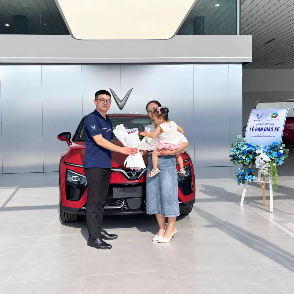 Khach Do Van Chi VF7 - Khách hàng nhận xe tháng 9/2026 tại VinFast Hưng Thịnh Phát tại Hưng Thịnh Phát Nhân viên trao hoa cho gia đình khách hàng nhận xe VinFast VF 7